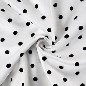 Macro detail of white silk-like fabric with elegant black polka dots and soft sheen