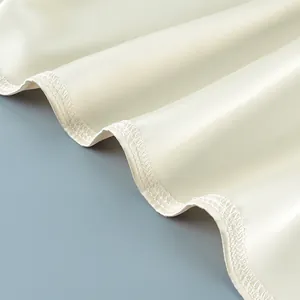 Detailansicht des eleganten gewellten Saums und der weißen Nähte an einem beigen Satinrock