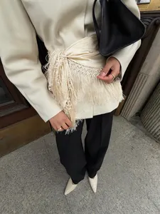 Detailansicht eines cremefarbenen Satin-Wickelrocks mit langen Fransen für einen schicken Look.