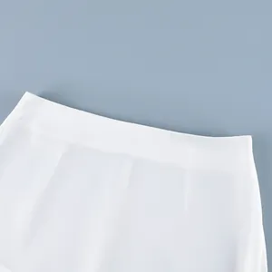 Detailopname van de minimalistische hoge tailleband van deze witte rechte lange rok