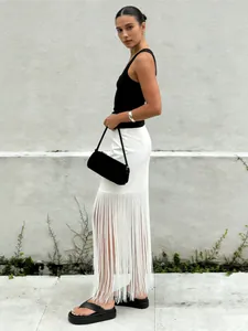 Zijaanzicht van een elegante witte rechte rok met lange franjes en een zwarte tanktop