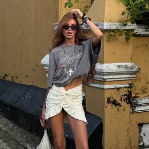 Λεπτομερής άποψη της λευκής μίνι φούστας με κόμπο και βολάν σε μοντέλο εξωτερικά.
