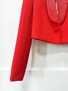 Primo piano di un blazer corto rosso con raffinato collo a scialle decorato con strass.