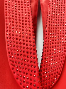 Dettaglio ravvicinato di un blazer rosso con collo a scialle e strass scintillanti