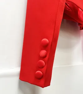 Primo piano della manica di un blazer rosso con quattro eleganti bottoni rivestiti.