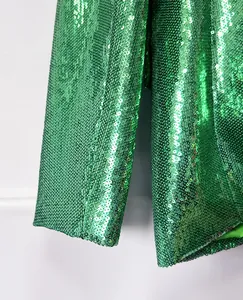 High-detail close-up of vibrant green sequined blazer sleeve and sparkling fabric texture.