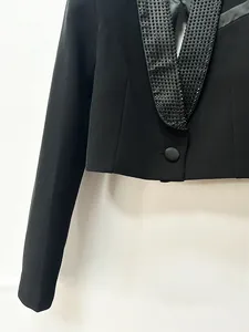 Dettaglio di un elegante blazer corto nero con collo a scialle decorato con strass.