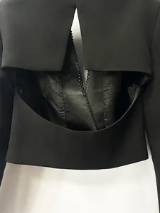 Primo piano di un blazer corto nero con design senza schienale e catena di strass