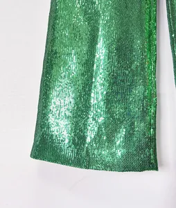 Detailed view of high-quality sparkling green sequin fabric on elegant flared trousers hem