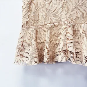 Primer plano de delicado tejido de encaje floral con elegante dobladillo de volantes en falda beige.