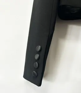 Dettaglio ravvicinato della manica di un blazer nero con quattro eleganti bottoni rivestiti