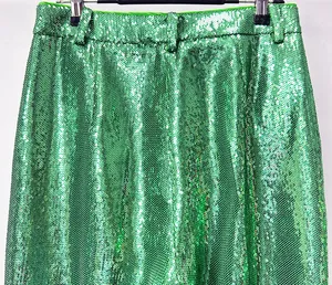 Close-up detail showing vibrant green sequins and waistband of high-end fashion trousers.