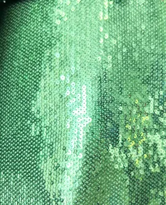 Macro detail of high-quality green sequins showing shimmering metallic fabric texture