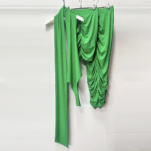 Close-up of vibrant green rhinestone knit fabric and detailed ruched skirt texture