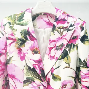 Close-up detail of white blazer with vibrant pink floral prints and green leaves