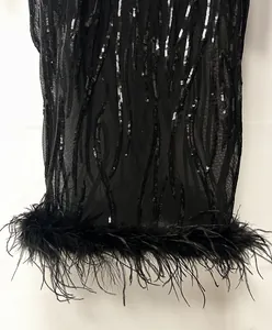 Detaillierte Nahaufnahme eines schwarzen Pailletten-Abendkleids mit echtem Federbesatz am Saum