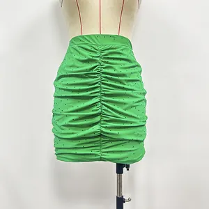 Detailed view of the bright green ruched mini skirt with shimmering rhinestone studs.