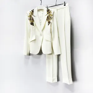Detailed macro view of the intricate gold beadwork on shoulders of an elegant white blazer