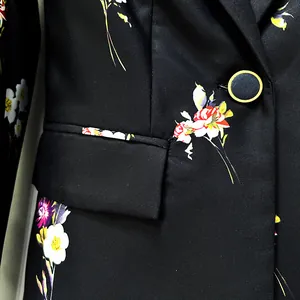Detailed macro view of elegant black blazer with vibrant floral print and gold-rimmed button