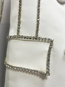 Detailed view of shimmering rhinestone trim on elegant white tailored blazer dress