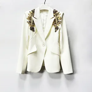 Detailed shot of heavy gold beaded embroidery on the shoulders of a white blazer.
