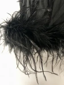 Eine Nahaufnahme von echten schwarzen Federn und Paillettennetz an einem Abendkleid