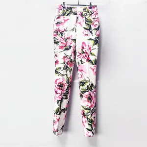 Close-up of white slim fit trousers with vibrant pink floral and green leaf pattern