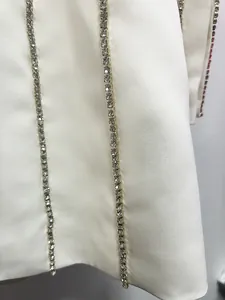Macro view of crystal rhinestone trim on white designer blazer dress fabric