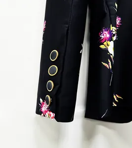 Close-up detail of black blazer sleeve with gold-rimmed buttons and floral print