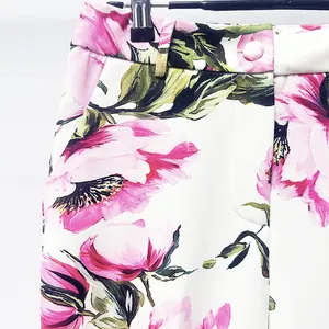 Close-up detail showing the high-waist floral print trousers with vibrant pink flower patterns
