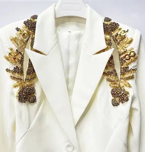 Close-up of elegant white blazer featuring intricate gold and bronze beaded shoulder detail