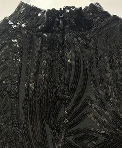 Detail eines schwarzen Pailletten-Abendkleids mit Stehkragen und Reißverschluss hinten