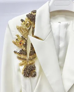 Detailed macro shot of luxury heavy beadwork on a white runway-style blazer shoulder.