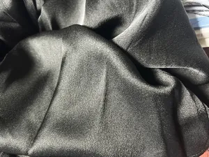 Nahaufnahme zeigt den glatten und glänzenden schwarzen Satinstoff eines Partykleides