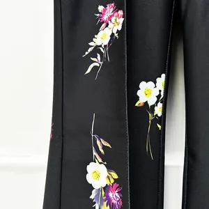 Detailed close-up view of vibrant floral patterns on premium black flared suit trousers.