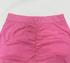 Close-up detail showing pink elastic knit ruched skirt with sparkling rhinestone pattern