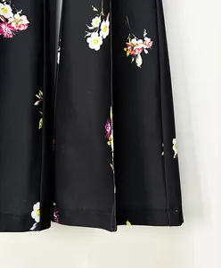 High-resolution close-up of black pleated fabric featuring a vibrant floral pattern.