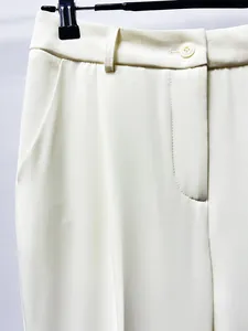 Detail of elegant cream high-waisted suit trousers showing fabric texture and button closure