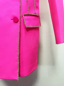Detailed macro view showing sparkling rhinestone trim on a hot pink luxury blazer dress.