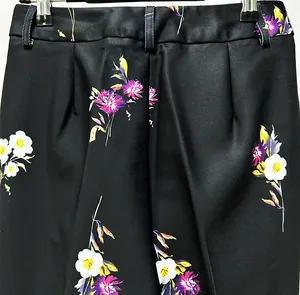 Detail view of elegant black high-waisted trousers featuring vibrant purple floral print