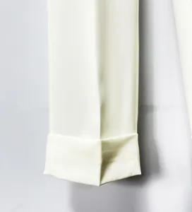 Detailed macro view of white slim-fit suit trousers featuring professional fold-over cuff design
