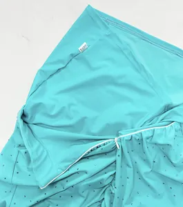 Close-up of turquoise knit fabric with sparkling rhinestones and hidden zipper detail