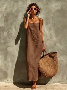 Mannequin portant une robe longue en coton et lin marron avec un grand sac en paille.