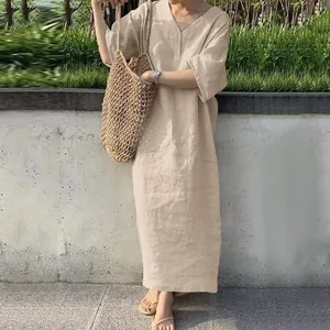 Gros plan robe longue beige col V en lin et coton, coupe ample avec sac tressé.