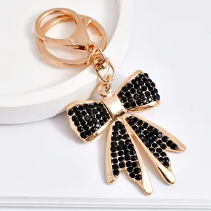 Detailed view of elegant gold-plated bow keychain with sparkling black rhinestones.