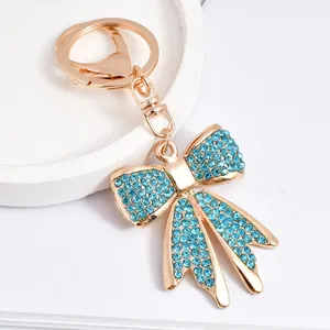 Detailed view of a gold-tone bowtie keychain with sparkling light-blue crystals.