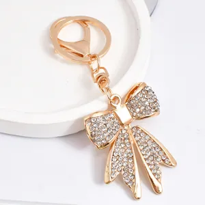 Close-up view of an elegant gold bow-tie keychain pendant encrusted with sparkling rhinestones