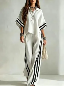 Vista completa de un elegante conjunto blanco de dos piezas con rayas negras en mangas y pantalón.