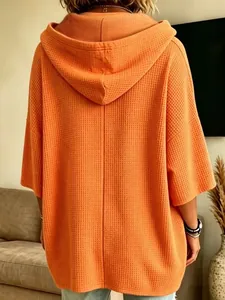 Vista posterior de una sudadera naranja extragrande con capucha de punto gofrado holgada.