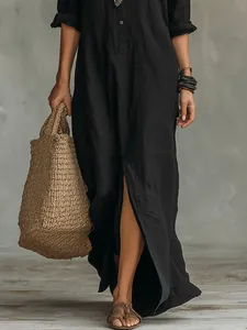 Close-up detail of black long-sleeved maxi dress featuring a front slit and linen texture